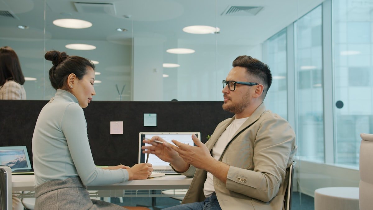 Two colleagues reviewing work together at a desk in a modern office