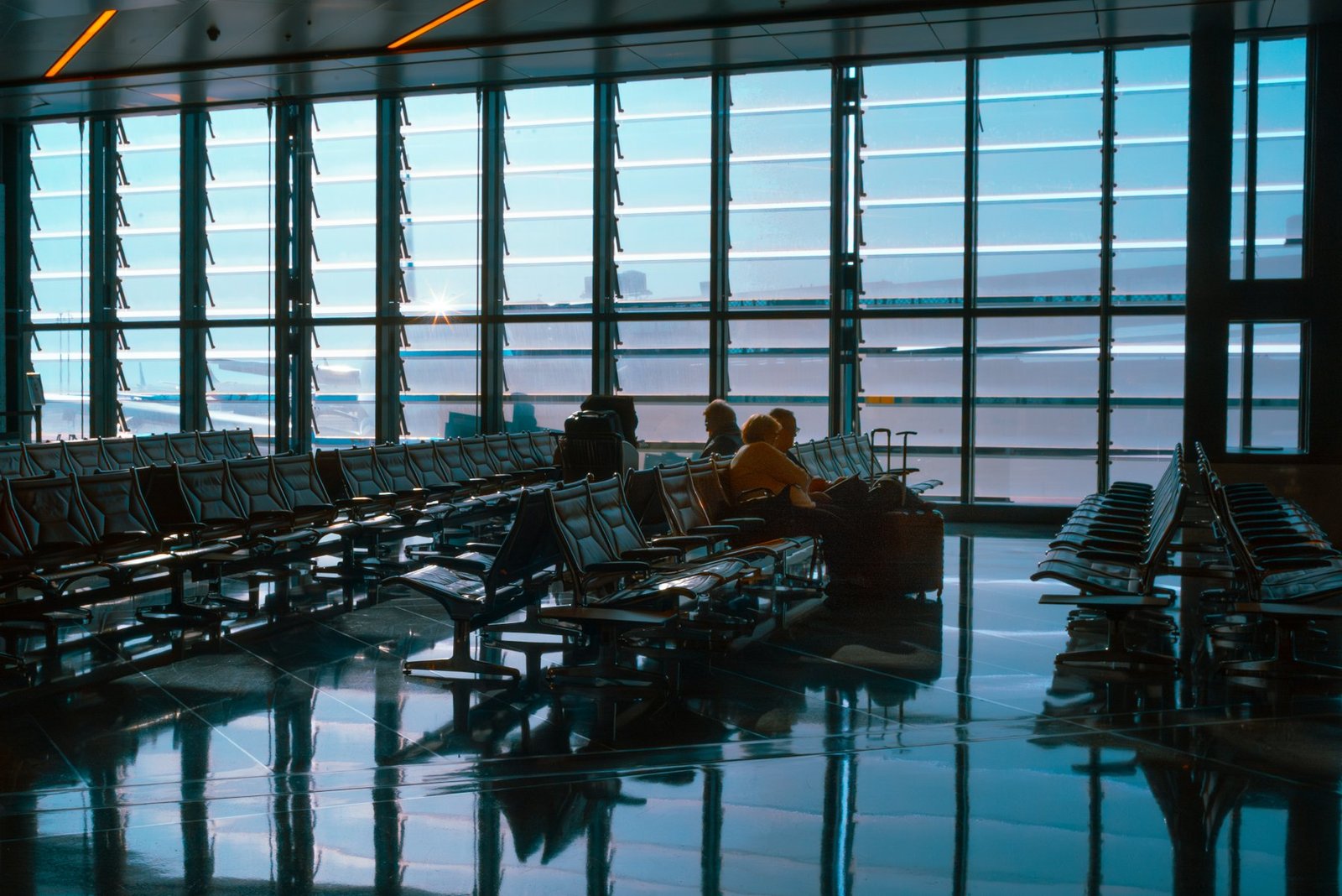 Empty airport terminal seating area with floor-to-ceiling windows at dusk